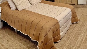 Ein Schlafzimmer mit Himmelsbett, einer kleinen Küchenzeile und einem runden Spiegel an der Wand.