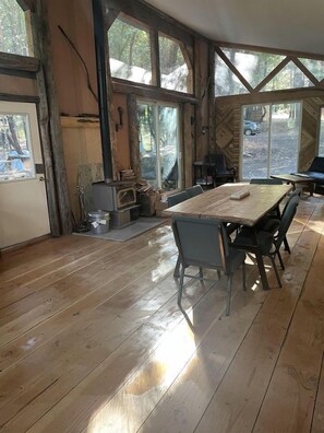 A rustic wooden interior with a large dining table, chairs, and a fireplace. - Charming Cabin for Sierra Nevada Getaways (Nevada City)