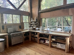 A rustic kitchen with wooden beams, a stove, and a sink.
