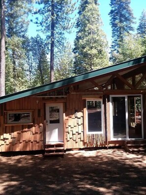 A rustic cabin with a wooden exterior, a front door, and a window.