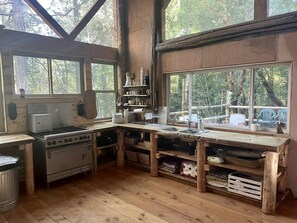 A rustic kitchen with wooden beams, a stove, and a sink.