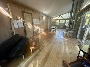 Ein Zimmer mit Holzboden, einer Couch, einem kleinen Tisch und einem Stuhl.