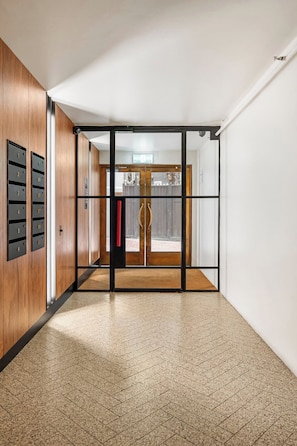 A hallway with a wooden wall, a glass door, and a tiled floor. - Luxury Villas The Lane Hideaway (Melbourne)