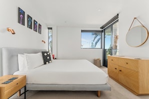 Ein modernes Schlafzimmer mit Bett, Nachttischen, einer Kommode und Bildern an der Wand.