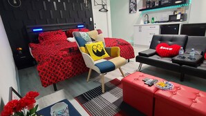 Ein modernes Wohnzimmer mit Bett, Sofa, Couchtisch und Küchenzeile.