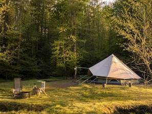 A tent set up in a grassy area with trees in the background.