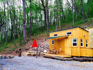 Eine Holzhütte mit Veranda, einer Bank und einem roten Schirm.
