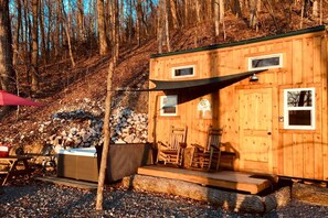 Een houten chalet met terras, twee ramen en een hottub.