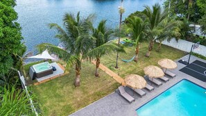 Un área de piscina con sillones reclinables, un jacuzzi y palmeras.