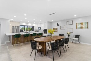 Una cocina moderna con armarios blancos, electrodomésticos de acero inoxidable y una isla central con taburetes de bar.