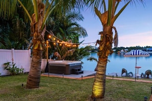 A backyard with a hot tub, palm trees, a pool, and string lights. - Lakefront Tropical Villa by Glam Homes  (North Miami Beach)