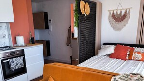 Una habitación de hotel moderna con sofá, cama, kitchenette y una pared decorativa.