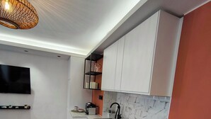 Una cocina moderna con armarios blancos, salpicadero de mármol, horno empotrado y encimera de madera.