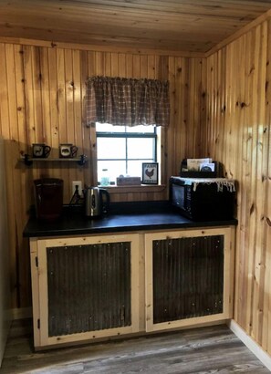 A wooden cabin-style kitchen with a window, a coffee maker, a toaster, and a microwave on the counter. - Cozy Cabin Rental near Ozark National Forest for a Relaxing Weekend Getaway in Arkansas (Harrison)