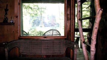 A wicker chair in front of a window with a view of trees.