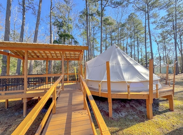 A wooden deck leading to a tent in a forested area. - Cozy Glamping Tent with Rain Shower in Calabash, North Carolina (Calabash)