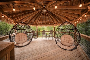 A wooden deck with hanging chairs and a thatched roof structure.