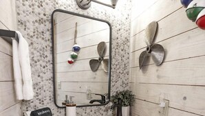 A bathroom with a wooden wall, a mirror, a sink, and a hanging light fixture. - Family-Friendly Yurt with Hot-Tub near to the Medina River in Bandera, Texas (Bandera)