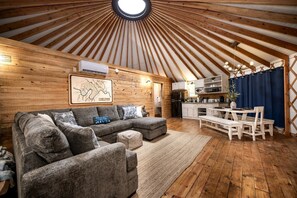 Un intérieur chaleureux avec un plafond en bois, un canapé, une table à manger et un coin cuisine.