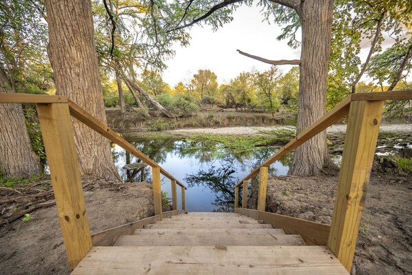 Una escalera de madera que lleva a un estanque rodeado de árboles.