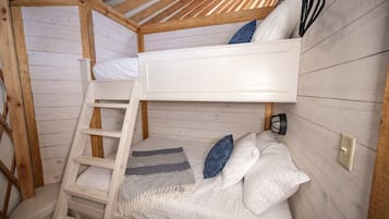 A bunk bed room with a ladder, pillows, and a blanket.