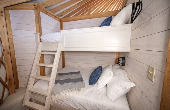 Habitación con literas, almohadas y una manta.