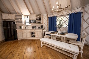 Une cuisine rustique avec des meubles en bois, un réfrigérateur noir et une table à manger avec des bancs.