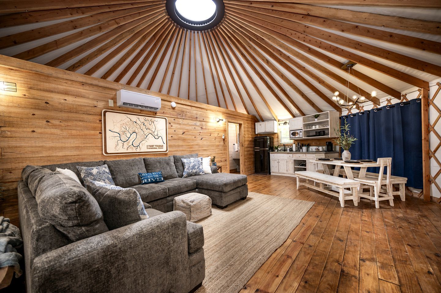Un interior acogedor con techo de madera, un sofá, una mesa de comedor y una zona de cocina.
