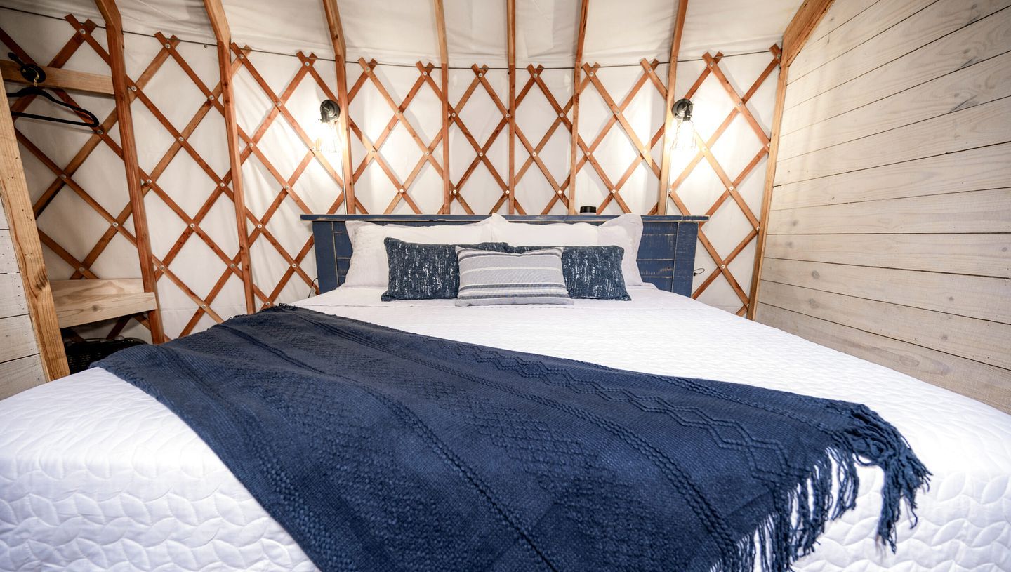 A bedroom with a bed, wooden walls, and a lattice ceiling.