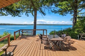 Eine Holzterrasse mit Tisch und Stühlen mit Blick auf einen See.