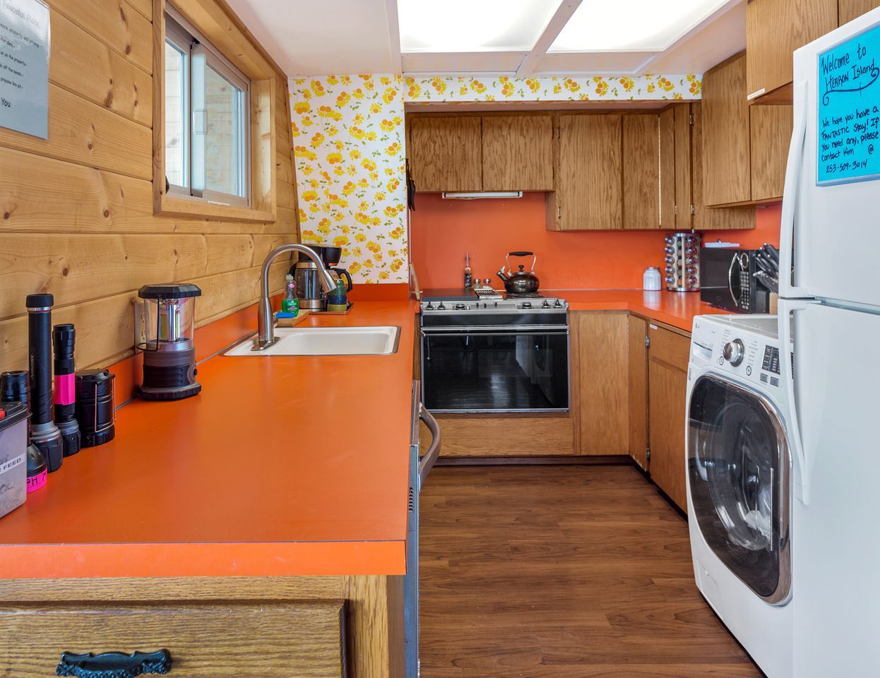 Cocina compacta con armarios de madera, un lavabo, una estufa, una lavadora y una ventana.