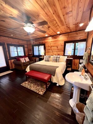 Ein Holzblockhaus-Innenraum mit Bett, Bank und Badezimmer.
