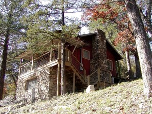 A stone cabin with a red exterior, wooden staircase, and a balcony. - Romantic Ozarks Cabin Rental in Secluded Woodland near Branson, Missouri (Hollister)