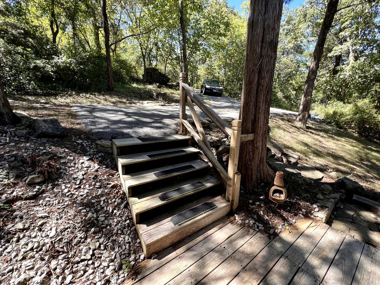 A wooden staircase leading up to a wooden deck surrounded by trees.