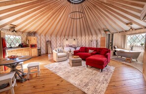 A yurt interior with a dining area, sofa, and a bathtub.