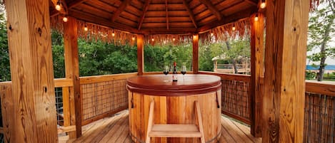 Un gazebo in legno con idromassaggio, un molo di legno e vista sul verde.