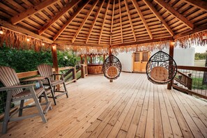 A wooden deck with hanging chairs and a thatched roof structure. - Love Bird Yurt Romantic, Hot Tub, by the River in Bandera, Texas (Bandera)