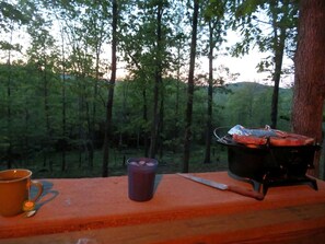 A camping setup with a portable stove, a mug, and a knife on a wooden surface.