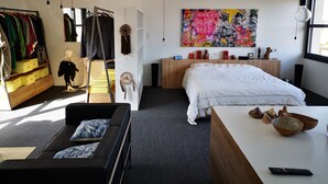 Una camera da letto moderna con un letto, una cassettiera, un armadio e un quadro astratto dai colori vivaci al muro.