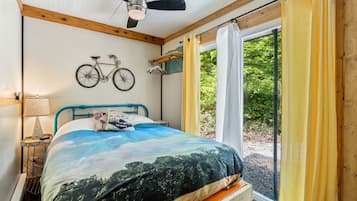 Ein Schlafzimmer mit Bett, Fahrrad, Deckenventilator und einem fenster mit Vorhängen.