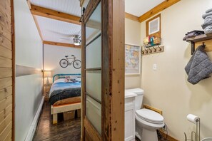 Una habitación pequeña con cama, una bicicleta, un inodoro y un estante con toallas.