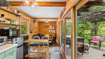 A compact kitchen with a dining area, wooden beams, and a view of the outdoors.