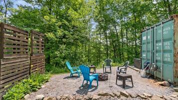 A gravel patio with outdoor seating, a wooden fence, and a green shipping container.