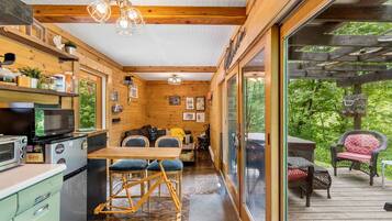 A compact kitchen with a dining area, wooden beams, and a view of the outdoors.