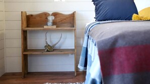 A bedroom with a wooden headboard, a shelf with a skull and antlers, and a bed with a striped blanket and pillows.