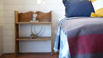 Ein Schlafzimmer mit einem hölzernen Kopfende, einem Regal mit Schädel und Geweihen sowie einem Bett mit einer gestreiften Decke und Kissen.