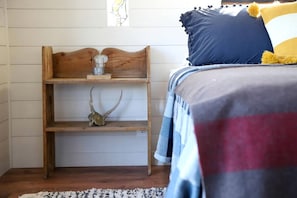 A bedroom with a wooden headboard, a shelf with a skull and antlers, and a bed with a striped blanket and pillows.