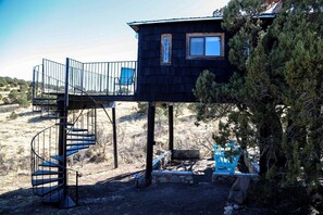 Una cabaña de dos pisos con una escalera en espiral que conduce a un balcón.