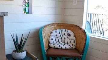 A corner room with a wicker chair, a small table with a plant, and a window with a view.