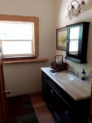 A bathroom with a window, a sink, a mirror, and a towel rack.